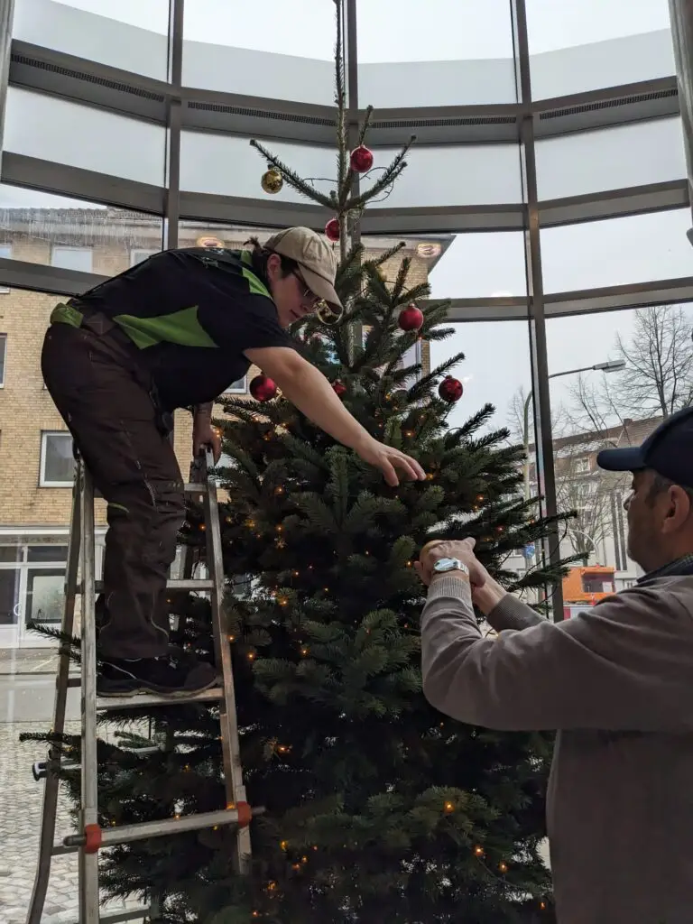 Foto von 2 Personen, die einen Weihnachtsbaum schmücken.