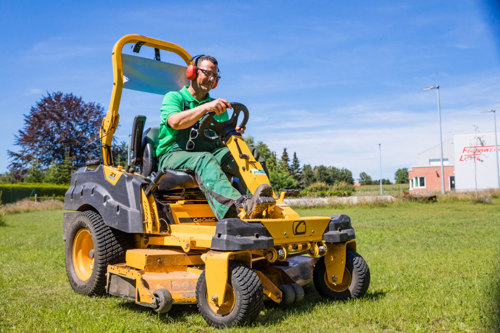 Foto von einem Cub Cadet Aufsitzrasenmäher mit Maschinenführer auf einer Rasenfläche.