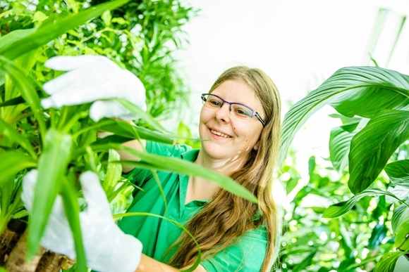 Foto von Mitarbeiterin Daniela Schmidt zwischen Pflanzen.