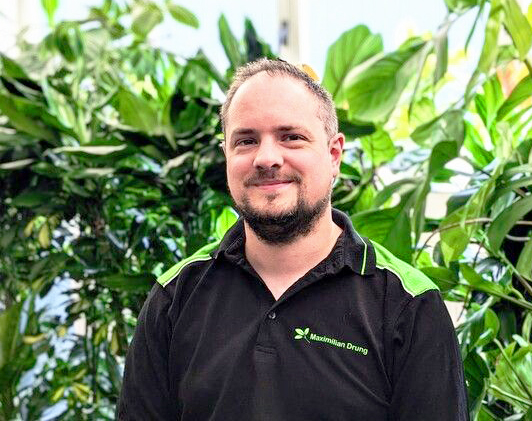 Foto von Mitarbeiter Maximilian Drung zwischen Pflanzen.