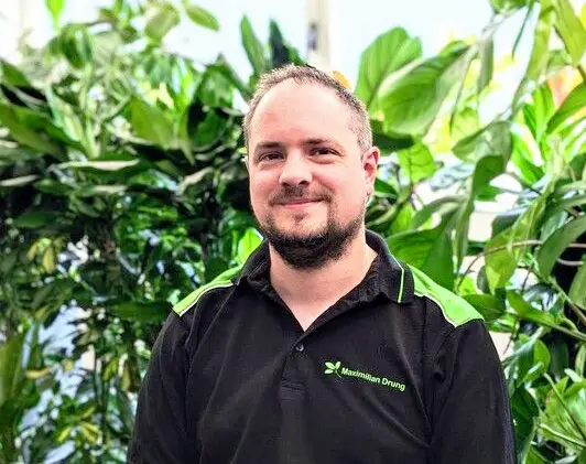 Foto von Mitarbeiter Maximilian Drung zwischen Pflanzen.